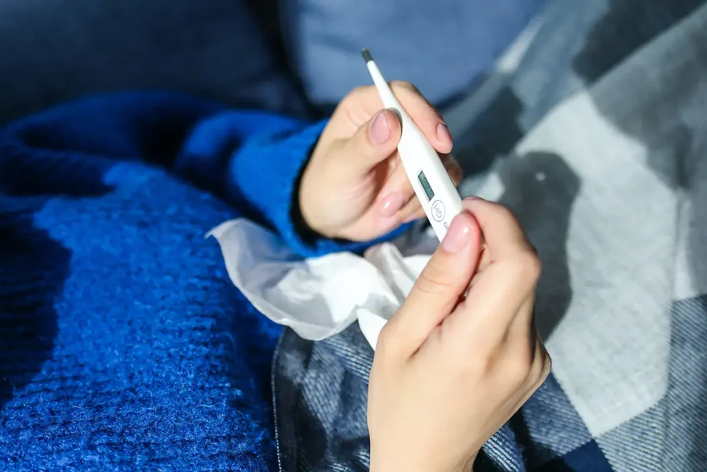Sick person looking at digital thermometer