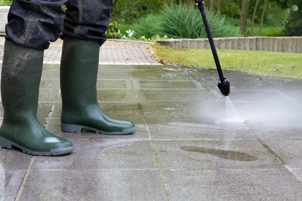 Power washer being used to clean concrete patio or walkway