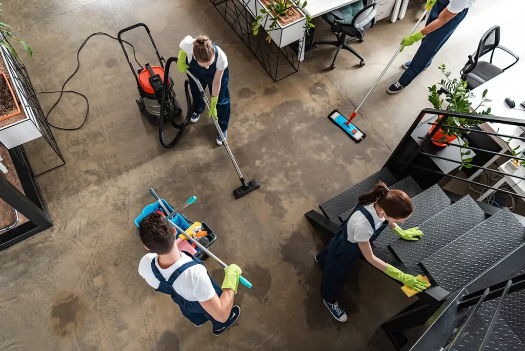 Team of janitors cleaning floor in a modern open plan office