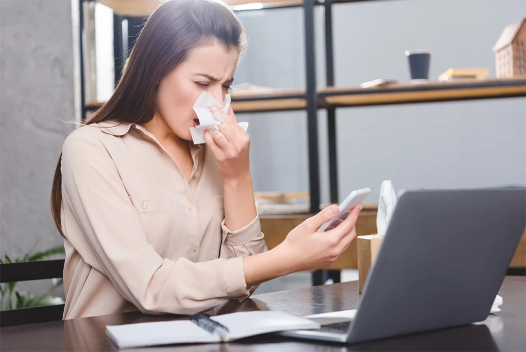 Woman in an office suffering from allergies.