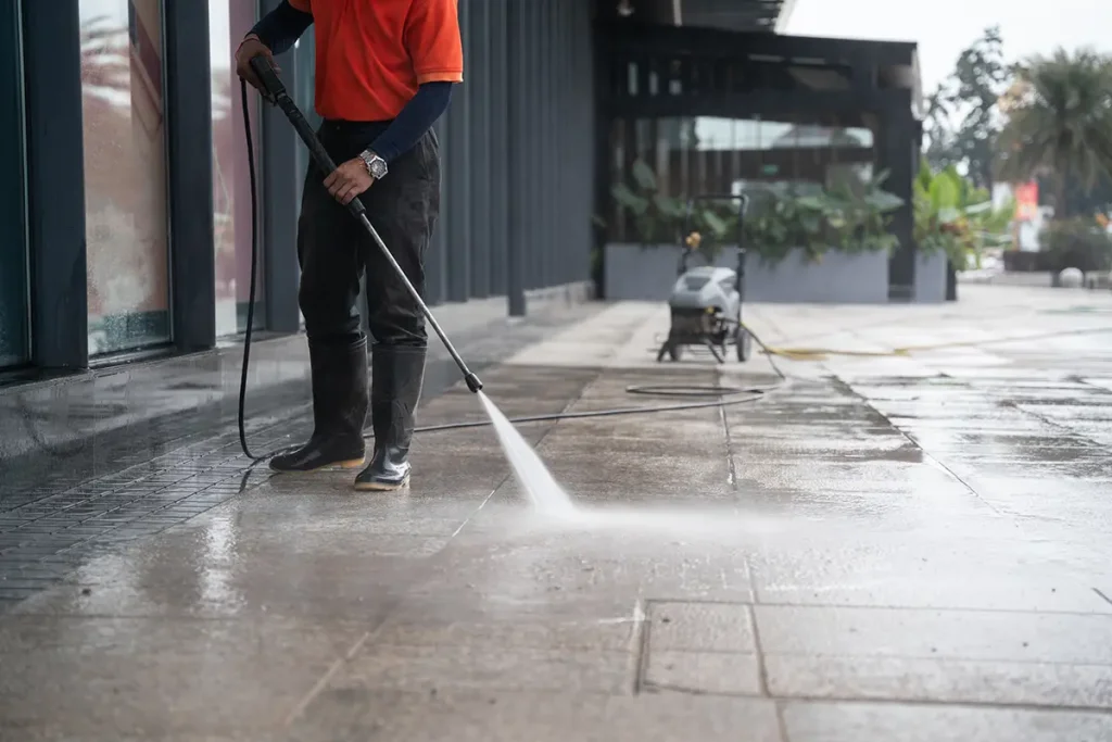 Cleaning staff washing the concrete floor with high-pressure water jets.