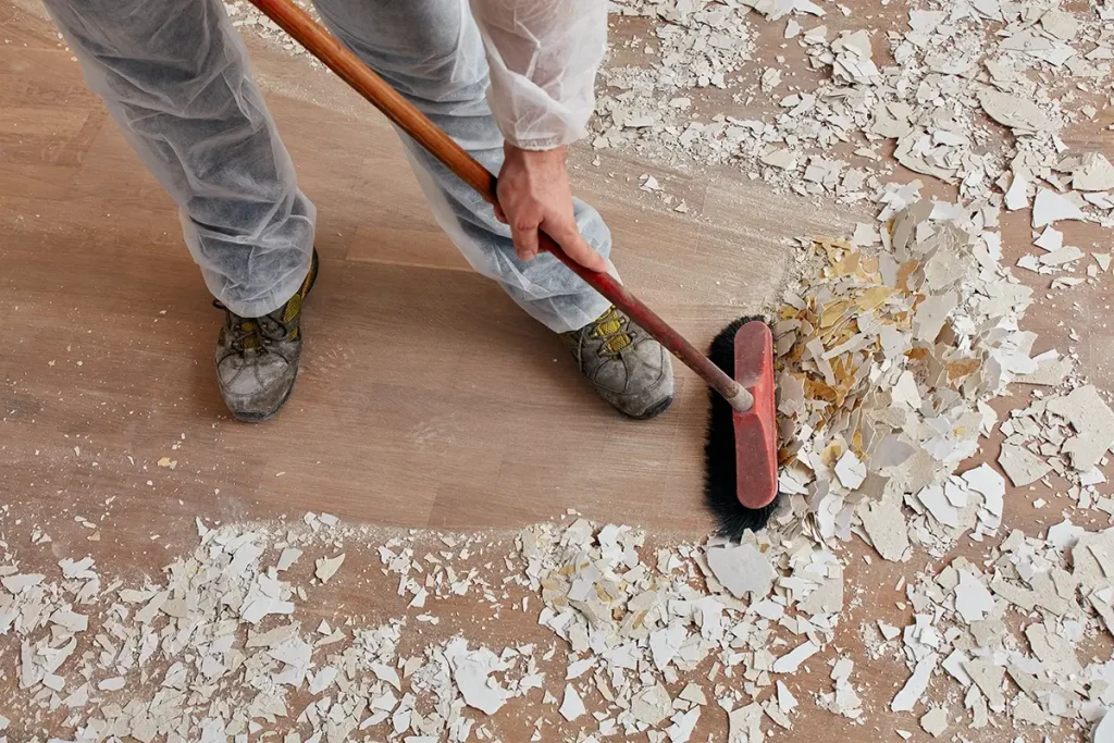 Person sweeping construction scraps off wood floor,