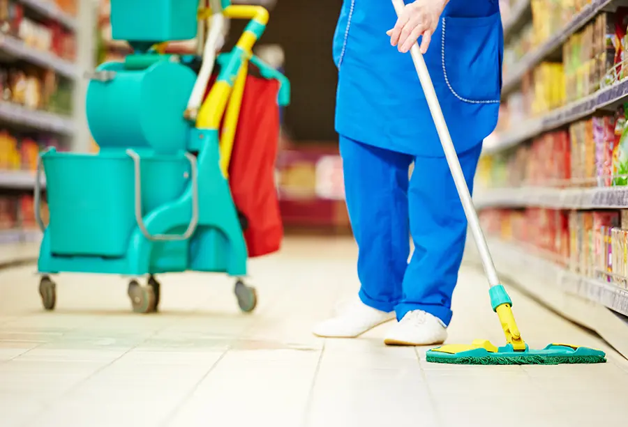 Person using a mop to clean the floor in a grocery or convivence store